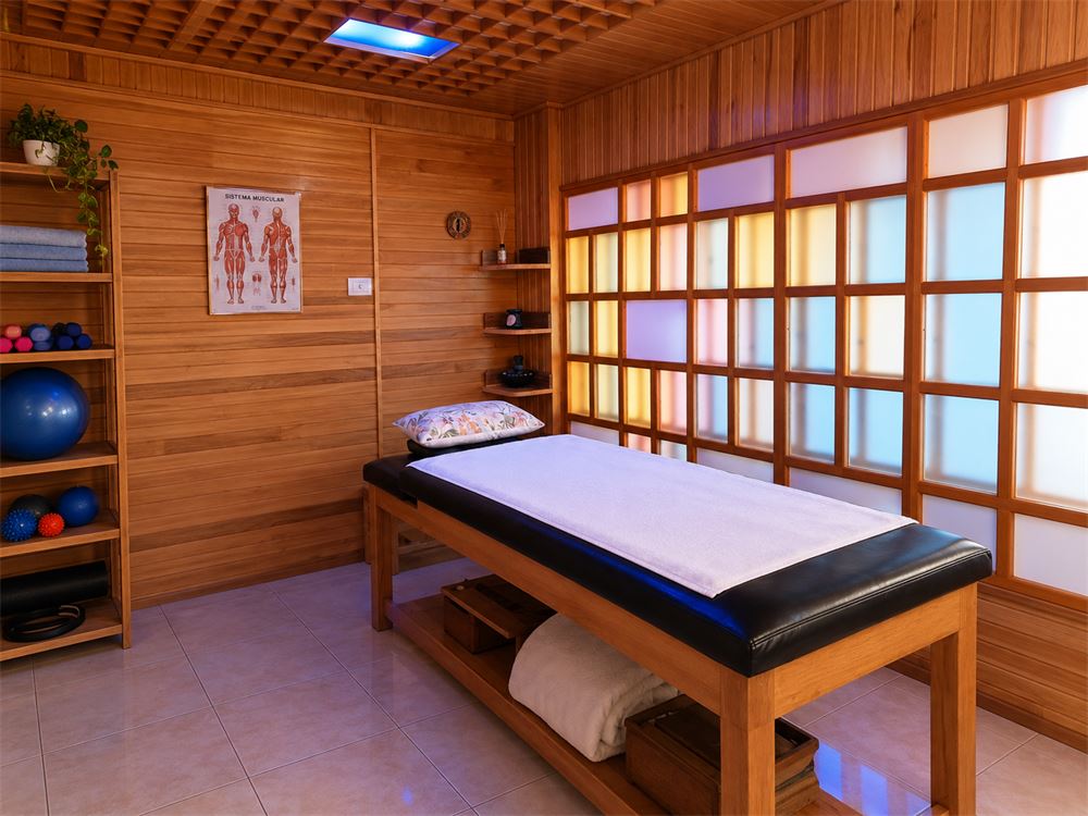 Sala de madera con camilla y paneles de vidrio de colores